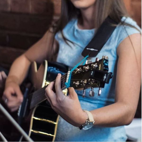Dziewczyna w niebieskiej bluzce gra na gitarze