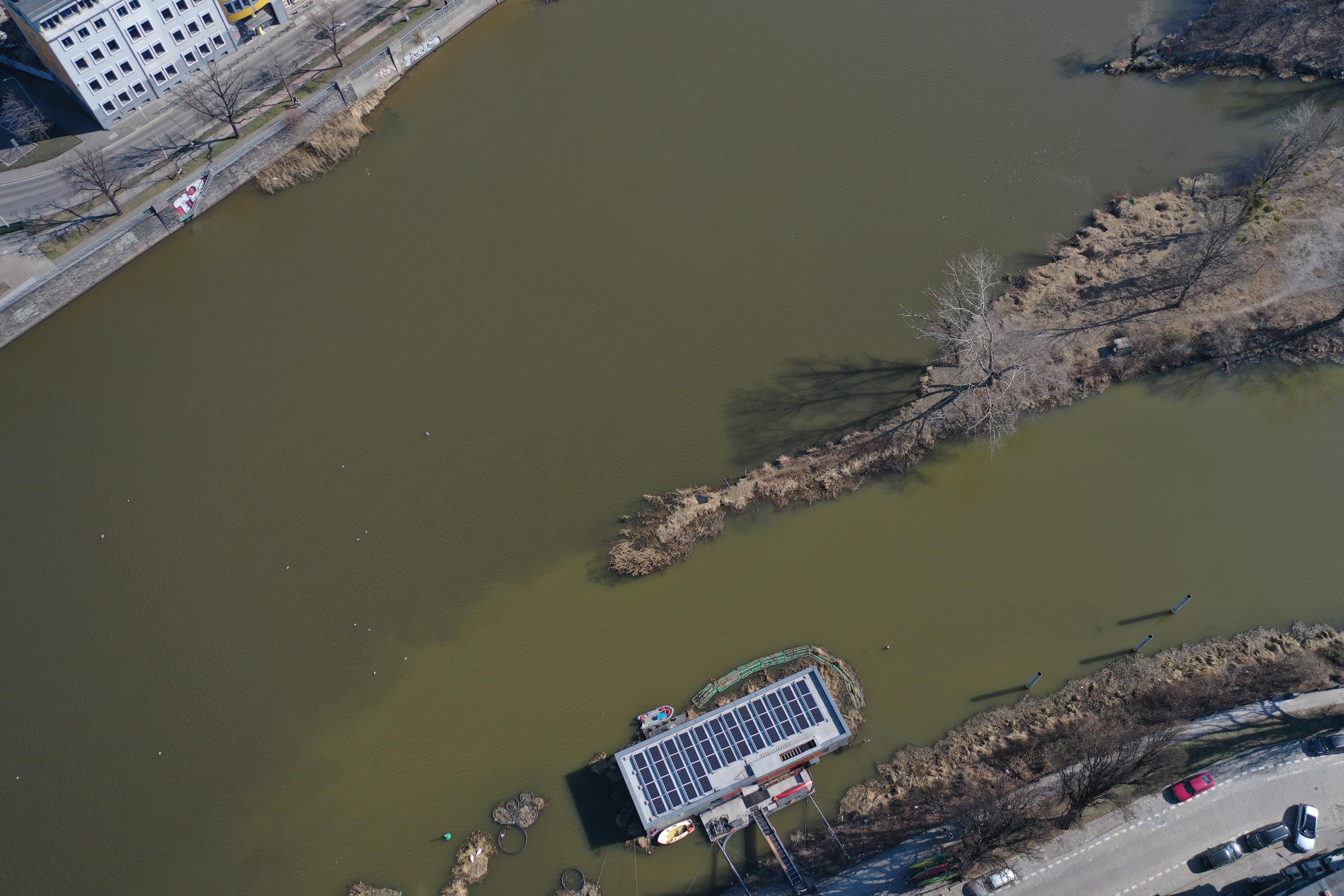 Widok z lotu ptaka na dom na wodzie, na którym ułożone zostały panele fotowoltaiczne. 