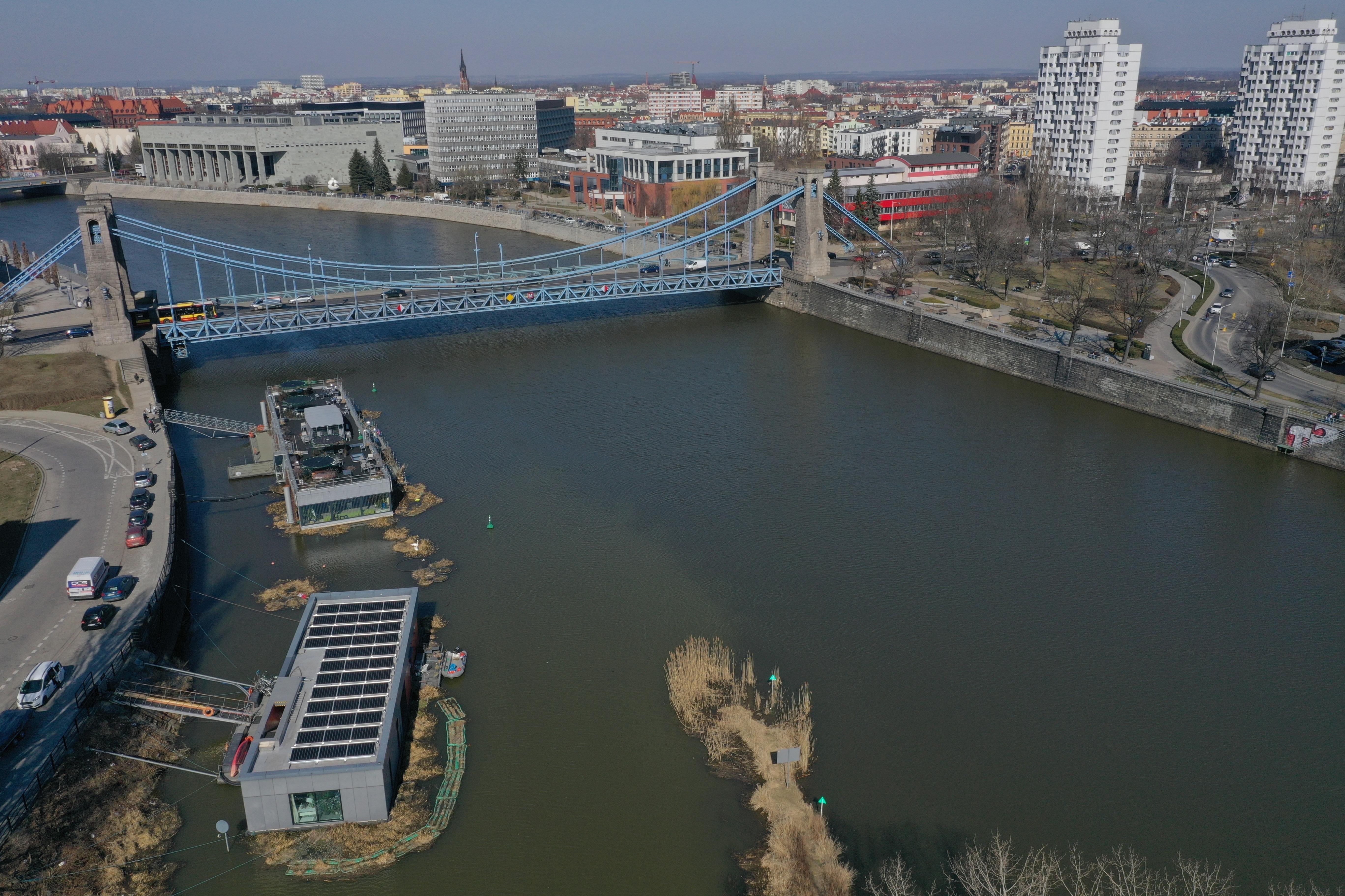 Widok z lotu ptaka na domy na wodzie. W tle most Grunwaldzki i rzeka Odra.