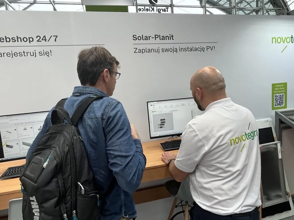 Dwóch mężczyzn stoi przed komputerem na stoisku, na targach ENEX. Jeden z nich prezentuje narzędzie do planowania instalacji fotowoltaicznych Solar-Planit.